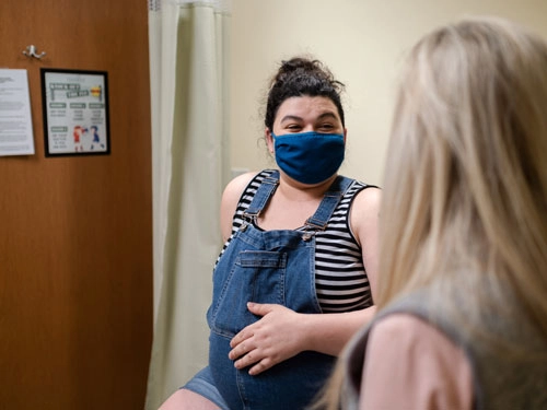 Pregnant woman wearing a mask in a doctor's office during a wellness checkup